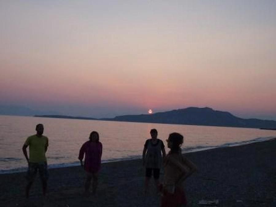 people learning and listening to a woman giving lesson of Tai Chi on beach in sunset at Korogonas Ark area